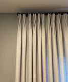 Beige curtains hanging against a plain wall