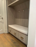 Wooden bench with storage drawers in a room with wooden flooring and white walls.Custom bench cushion