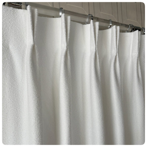 Close-up of a tailored pleat custom bouclé drapery panel in an ivory color.
