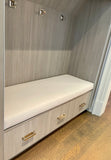Mudroom with built-in bench and storage drawers against a wooden wall. Designer bench cushion