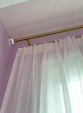 White curtain with a gold rod against a purple wall 
Sheer curtain 