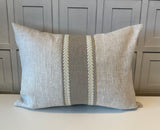 Gray pillow with a decorative white stripe on a neutral background 
High quality linen lumbar pillow with Fabricut Amelie Natural trim and Canadian white goose feather insert
